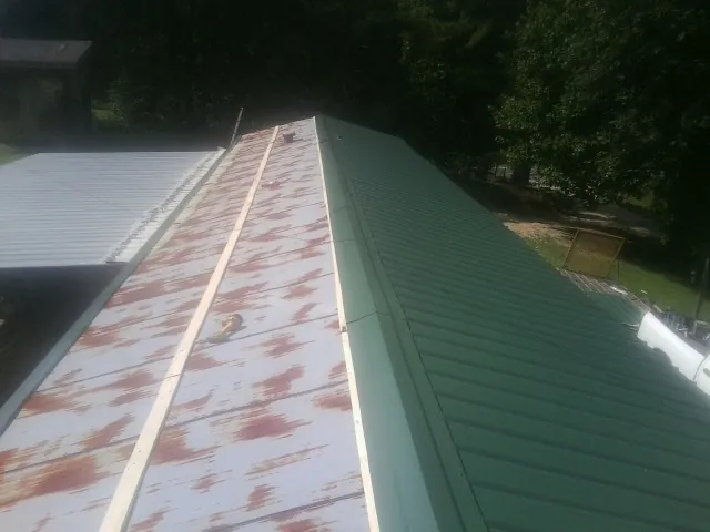 Old rusted panels beside newly installed green metal roofing — Wind Damage Roof Repair by Roofing Brothers in Kansas City