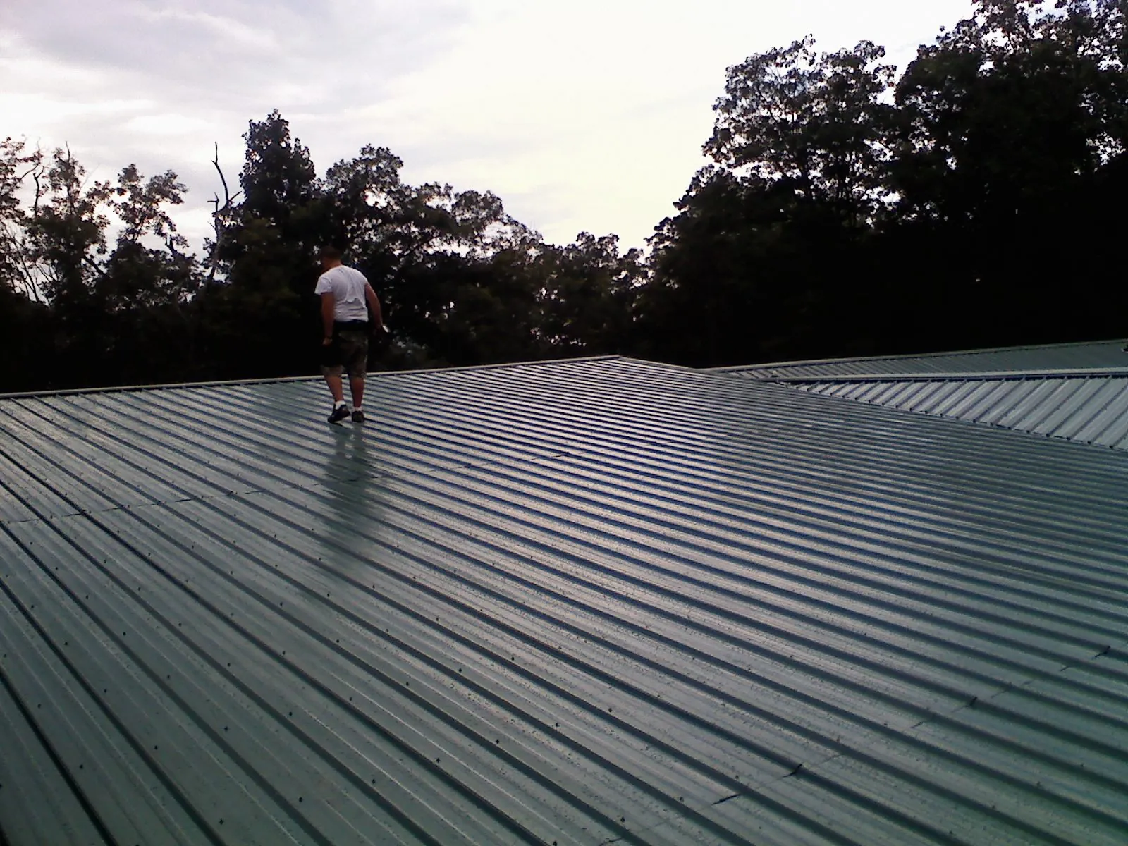 Roofer walking a wide expanse of new green metal roofing in Kansas City